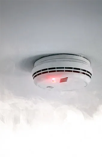 Licensed Brisbane electrician fitting an interconnected photoelectric smoke alarm to a ceiling