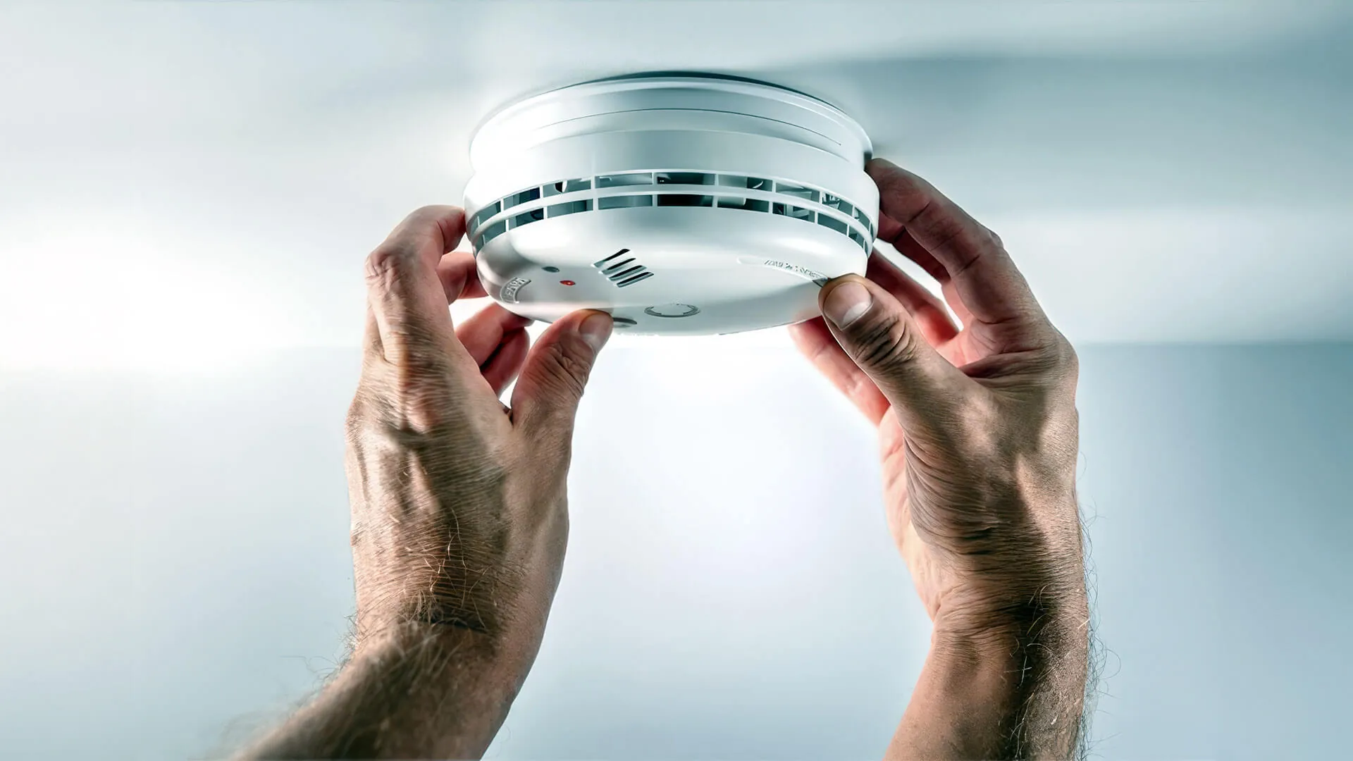 Electrician marking smoke alarm positions along a Brisbane hallway ceiling